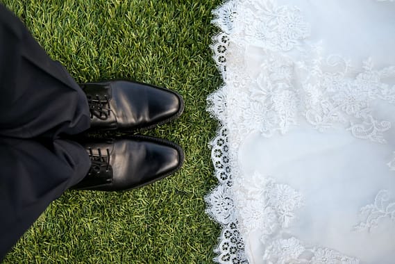 les maries debout en face a face detail chaussures noirs et bas de robe de mariee